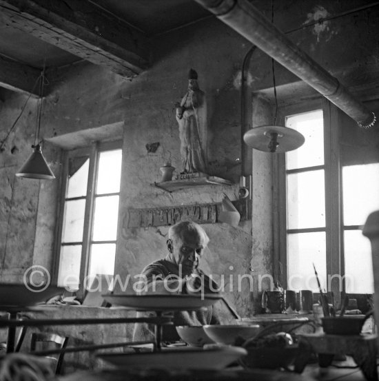 Picasso at work at the Madoura pottery in Vallauris. Above him is a statue of St-Claude, the patron saint of the potters, whose name was given to Picasso's younger son. Vallauris 23.3.53 - Photo by Edward Quinn