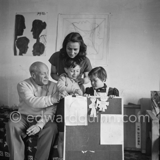 Encouraged by his father, Claude Picasso tries to do a portrait of Pablo Picasso, portraying him with a round face, deep furrows on his forehead, a triangle for a nose, and streaks of hair on the sides of his head. La Galloise, Vallauris 16.4.1953. - Photo by Edward Quinn