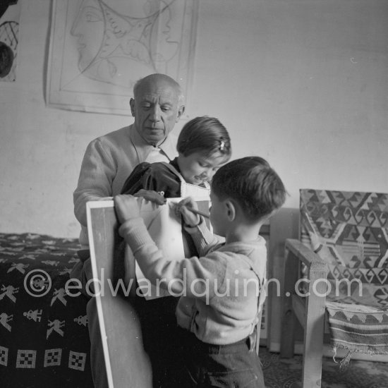 Encouraged by his father, Claude tries to do a portrait of Picasso, portraying him with a round face, deep furrows on his forehead. a triangle for a nose, and streaks of hair on the sides of his head. La Galloise, Vallauris 16 Apr 1953. - Photo by Edward Quinn