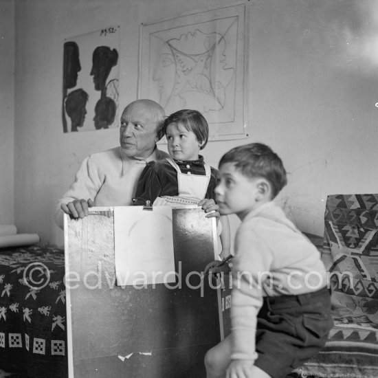 Encouraged by his father, Claude Picasso tries to do a portrait of Pablo Picasso, portraying him with a round face, deep furrows on his forehead, a triangle for a nose, and streaks of hair on the sides of his head. La Galloise, Vallauris 16.4.1953. - Photo by Edward Quinn