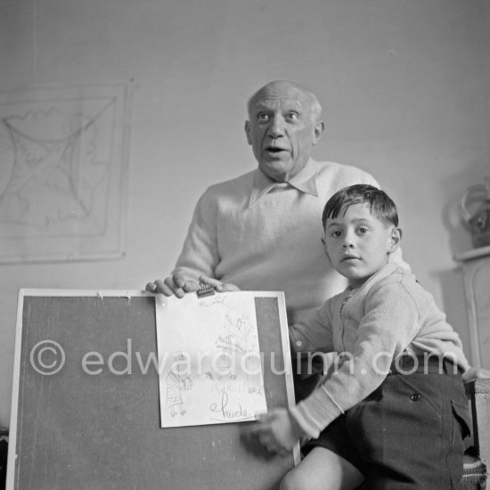 Encouraged by his father, Claude Picasso tries to do a portrait of Pablo Picasso, portraying him with a round face, deep furrows on his forehead, a triangle for a nose, and streaks of hair on the sides of his head. La Galloise, Vallauris 16.4.1953. - Photo by Edward Quinn