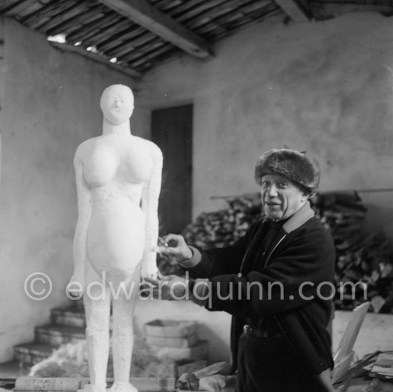 Pablo Picasso working on a plaster sculpture, "La femme enceinte". In winter, Pablo Picasso wore warm clothes inside the studio, as heating was minimized to prevent the sculptures from. drying too quickly. In his studio Le Fournas, Vallauris 1953. - Photo by Edward Quinn