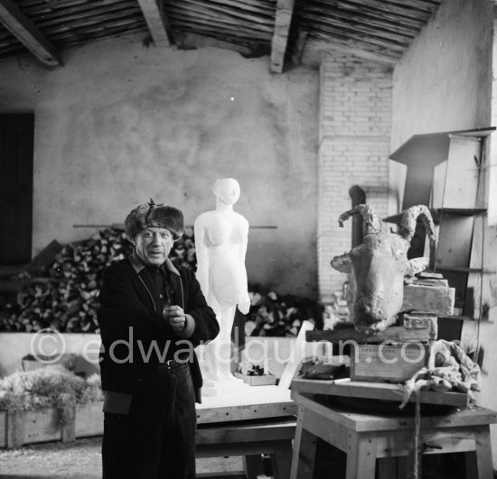 Pablo Picasso in his studio Le Fournas. In winter, Pablo Picasso wore warm clothes inside the studio, as heating was minimized to prevent the sculptures from drying too quickly., Vallauris 1953. - Photo by Edward Quinn