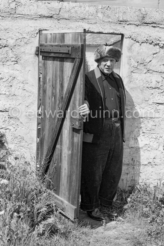 Pablo Picasso wearing a trapper\'s fur cap, at the door to Le Fournas, Vallauris 1953. - Photo by Edward Quinn