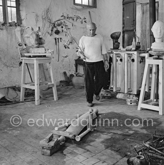 Pablo Picasso working in his sculpture studio Le Fournas making a sculpture figure with odds and ends from his scrap heap. Here he is adding a branch to the sculpture which was later replaced by a key. The finished sculpture got the name "La femme à la clé (La Taulière)" ("Woman with a key"). Le Fournas, Vallauris 1953. - Photo by Edward Quinn
