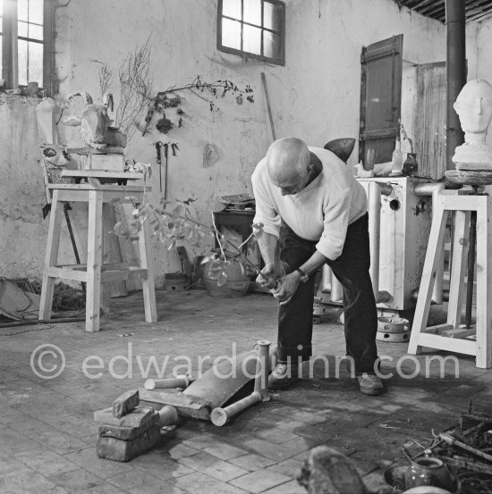 Pablo Picasso working in his sculpture studio Le Fournas making a sculpture figure with odds and ends from his scrap heap. Here he is adding a branch to the sculpture which was later replaced by a key. The finished sculpture got the name "La femme à la clé (La Taulière)" ("Woman with a key"). Le Fournas, Vallauris 1953. - Photo by Edward Quinn