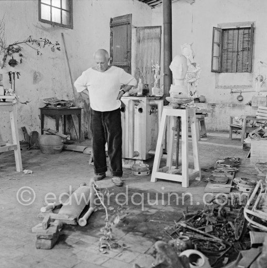 Pablo Picasso working in his sculpture studio Le Fournas making a sculpture figure with odds and ends from his scrap heap. Here he is adding a branch to the sculpture which was later replaced by a key. The finished sculpture got the name "La femme à la clé (La Taulière)" ("Woman with a key"). Le Fournas, Vallauris 1953. - Photo by Edward Quinn