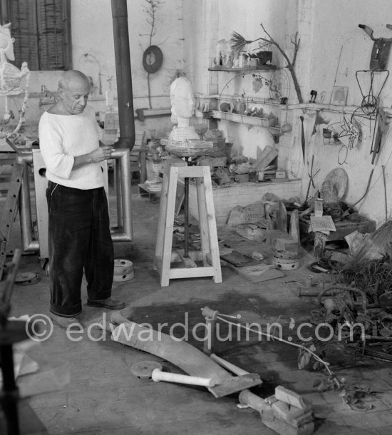 Pablo Picasso working in his sculpture studio Le Fournas making a sculpture figure with odds and ends from his scrap heap. Here he is adding a branch to the sculpture which was later replaced by a key. The finished sculpture got the name "La femme à la clé (La Taulière)" ("Woman with a key"). Le Fournas, Vallauris 1953. - Photo by Edward Quinn