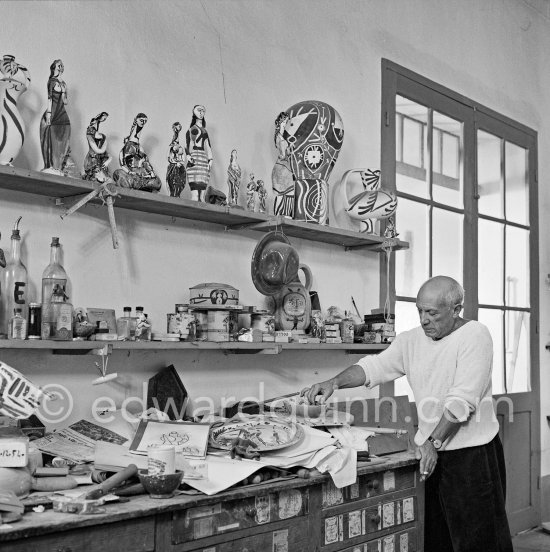 Pablo Picasso in front of a board with ceramics. Le Fournas, Vallauris 1953. - Photo by Edward Quinn