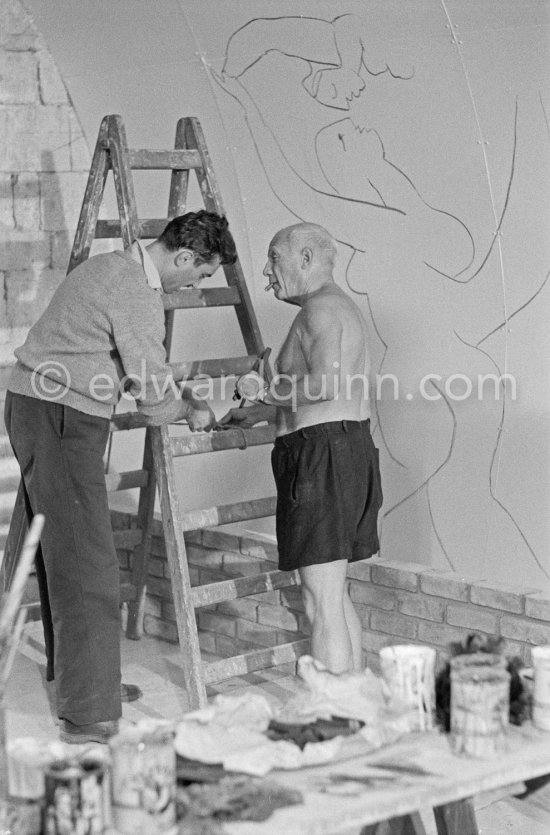 Pablo Picasso working on the "War and Peace study" drawings on the wall of Chapelle de la Paix (or Temple de la Paix) for the documentary film of Luciano Emmer (left). (The panels of War and Peace of 1952 were away on exhibition). Vallauris 1953. - Photo by Edward Quinn