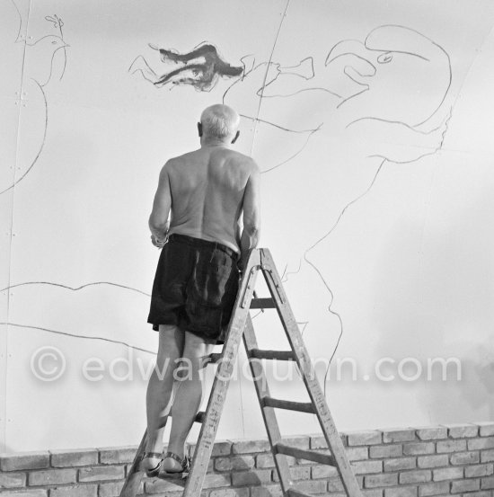 Pablo Picasso working on the "War and Peace study" drawings on the wall of Chapelle de la Paix (or Temple de la Paix) for the documentary film of Luciano Emmer. (The panels of War and Peace of 1952 were away on exhibition). Vallauris 1953. - Photo by Edward Quinn