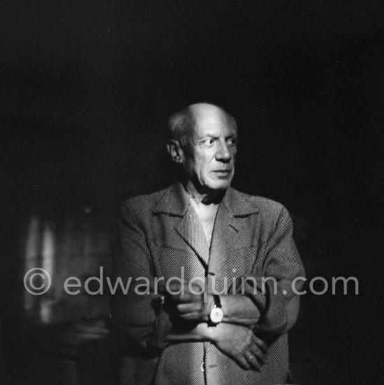 Pablo Picasso standing in a shaft of light that shone through an opening in the wall of Chapelle de la Paix. During filming of Pablo Picasso working on the "War and Peace study" drawings on the wall of Chapelle de la Paix (or Temple de la Paix). Documentary film by Luciano Emmer. Vallauris 1953. - Photo by Edward Quinn