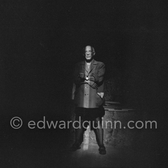 Pablo Picasso standing in a shaft of light that shone through an opening in the wall of Chapelle de la Paix. During filming of Pablo Picasso working on the "War and Peace study" drawings on the wall of Chapelle de la Paix (or Temple de la Paix). Documentary film by Luciano Emmer. Vallauris 1953. - Photo by Edward Quinn