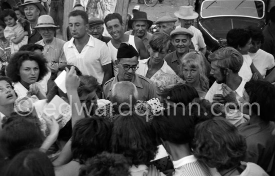 Sylvette David, the twenty year old model of Pablo Picasso, looking towards the camera, Toby Jellinek (right). Pablo Picasso with flower shirt signing autographs. First Corrida of Vallauris, organized by Pablo Picasso Vallauris 1954. - Photo by Edward Quinn