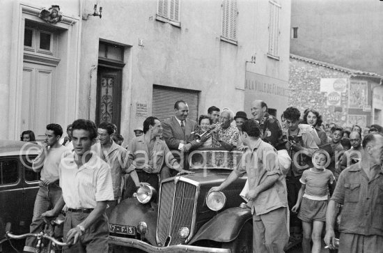 Among the locals in Vallauris, Pablo Picasso sets the pace at the festival by showing his "skill" on the trumpet, which he could not play at all. At the parade which proceeded the bullfight staged by Pablo Picasso at Vallauris 1954. Car: Mathis EMY 4-S 1934 Saint Moritz - Photo by Edward Quinn