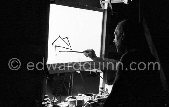 During filming of "Le mystère Picasso". Pablo Picasso working on "Nature morte". Pablo Picasso had a frame constructed on which he could stretch a transluscent piece of paper. He drew on one side, and the camera filmed the drawing being born from the other side. Nice, Studios de la Victorine 1955. - Photo by Edward Quinn