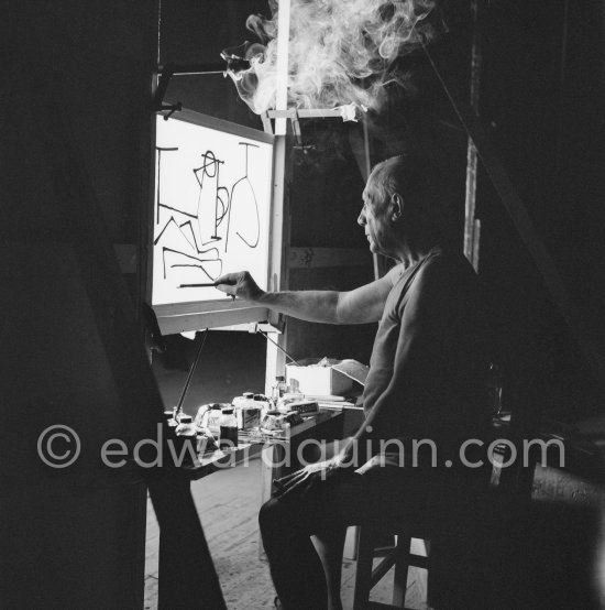 During filming of "Le mystère Picasso". Pablo Picasso working on "Nature morte". Pablo Picasso had a frame constructed on which he could stretch a transluscent piece of paper. He drew on one side, and the camera filmed the drawing being born from the other side. Nice, Studios de la Victorine 1955. - Photo by Edward Quinn