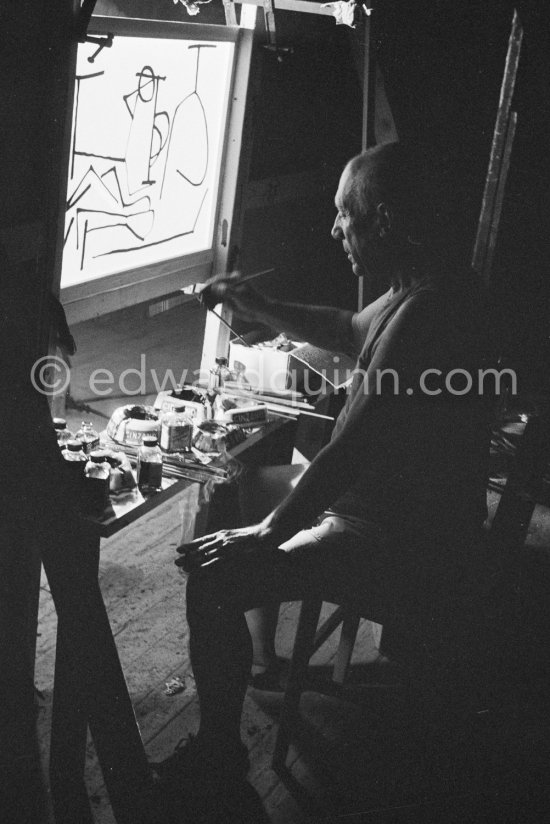During filming of "Le mystère Picasso". Pablo Picasso working on "Nature morte". Pablo Picasso had a frame constructed on which he could stretch a transluscent piece of paper. He drew on one side, and the camera filmed the drawing being born from the other side. Nice, Studios de la Victorine 1955. - Photo by Edward Quinn
