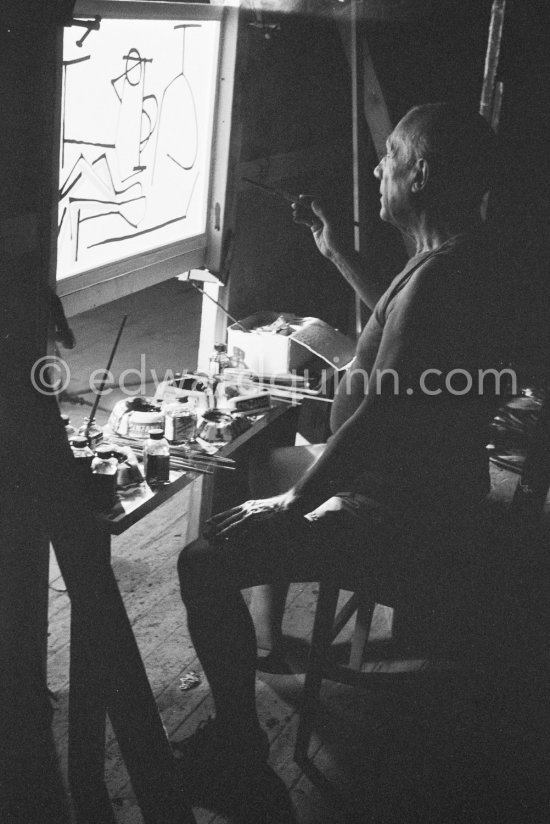 During filming of "Le mystère Picasso". Pablo Picasso working on "Nature morte". Pablo Picasso had a frame constructed on which he could stretch a transluscent piece of paper. He drew on one side, and the camera filmed the drawing being born from the other side. Nice, Studios de la Victorine 1955. - Photo by Edward Quinn