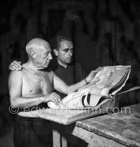 Pablo Picasso and Henri-Georges Clouzot studying a catalog of tapestries. Pablo Picasso used cut-outs for the two paintings "Nature morte sur une commode", 1955 and "Femme nue allongé" or "Grand nu allongé". Nice, Studios de la Victorine, 1955. - Photo by Edward Quinn