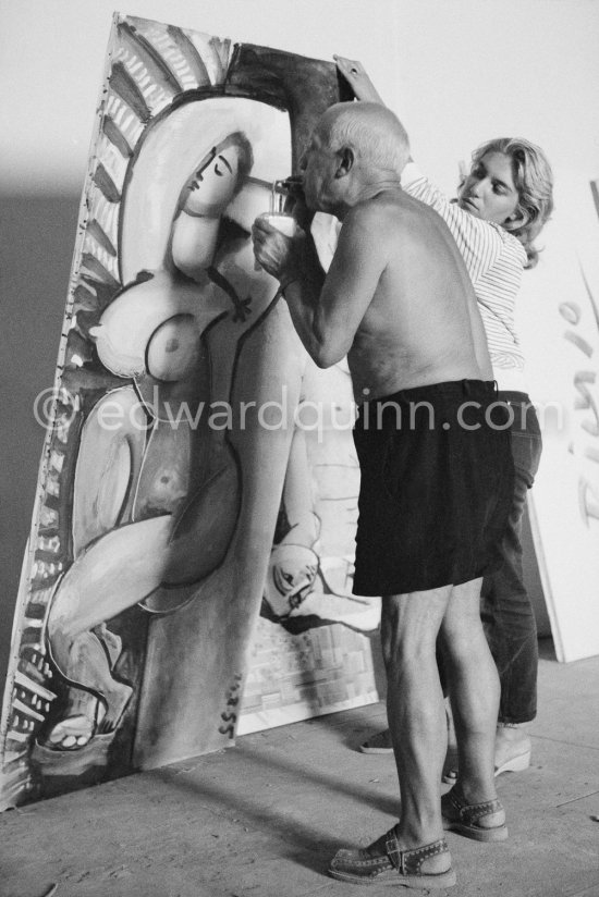 Pablo Picasso and Maya Picasso with painting "Femme nue allongée" or "Grand nu allongé aux bras croisés" during filming of "Le mystère Picasso", documentary. Nice, Studios de la Victorine, 1955. - Photo by Edward Quinn