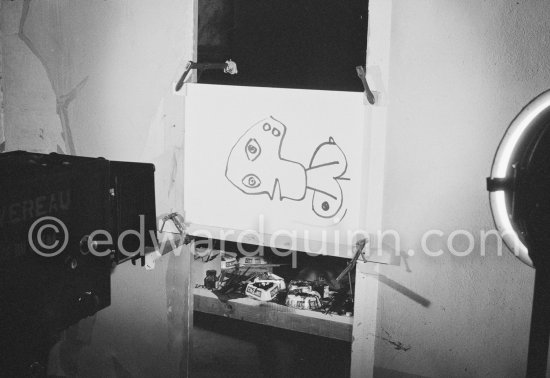 During filming of "Le mystère Picasso". Pablo Picasso working on "Tête de femme" with colored ink. He had a frame constructed on which he could stretch a transluscent piece of paper. He drew on one side, and the camera filmed the drawing being born from the other side. Nice, Studios de la Victorine 1955. - Photo by Edward Quinn