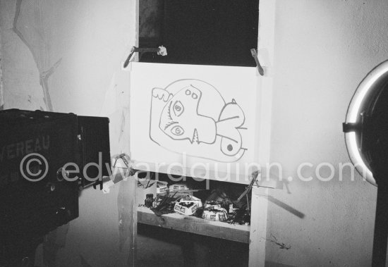 During filming of "Le mystère Picasso". Pablo Picasso working on "Tête de femme" with colored ink. He had a frame constructed on which he could stretch a transluscent piece of paper. He drew on one side, and the camera filmed the drawing being born from the other side. Nice, Studios de la Victorine 1955. - Photo by Edward Quinn