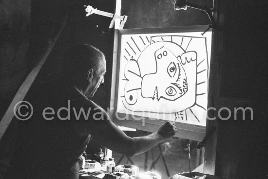 During filming of "Le mystère Picasso". Pablo Picasso working on "Tête de femme" with colored ink. He had a frame constructed on which he could stretch a transluscent piece of paper. He drew on one side, and the camera filmed the drawing being born from the other side. Nice, Studios de la Victorine 1955. - Photo by Edward Quinn