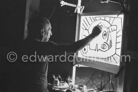 During filming of "Le mystère Picasso". Pablo Picasso working on "Tête de femme" with colored ink. He had a frame constructed on which he could stretch a transluscent piece of paper. He drew on one side, and the camera filmed the drawing being born from the other side. Nice, Studios de la Victorine 1955. - Photo by Edward Quinn