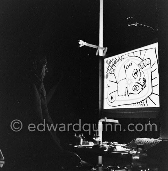 During filming of "Le mystère Picasso". Pablo Picasso working on "Tête de femme" with colored ink. He had a frame constructed on which he could stretch a transluscent piece of paper. He drew on one side, and the camera filmed the drawing being born from the other side. Nice, Studios de la Victorine 1955. - Photo by Edward Quinn