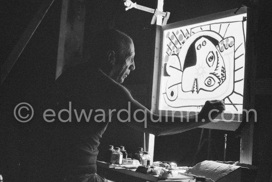 During filming of "Le mystère Picasso". Pablo Picasso working on "Tête de femme" with colored ink. He had a frame constructed on which he could stretch a transluscent piece of paper. He drew on one side, and the camera filmed the drawing being born from the other side. Nice, Studios de la Victorine 1955. - Photo by Edward Quinn