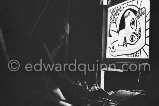 During filming of "Le mystère Picasso". Pablo Picasso working on "Tête de femme" with colored ink. He had a frame constructed on which he could stretch a transluscent piece of paper. He drew on one side, and the camera filmed the drawing being born from the other side. Nice, Studios de la Victorine 1955. - Photo by Edward Quinn