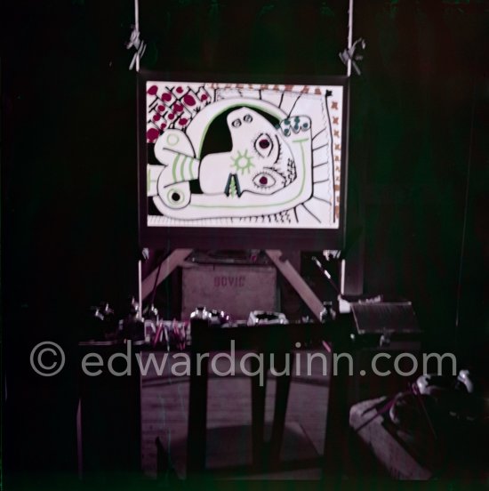 During filming of "Le mystère Picasso". Pablo Picasso working on "Tête de femme" with colored ink. He had a frame constructed on which he could stretch a transluscent piece of paper. He drew on one side, and the camera filmed the drawing being born from the other side. Nice, Studios de la Victorine 1955. - Photo by Edward Quinn