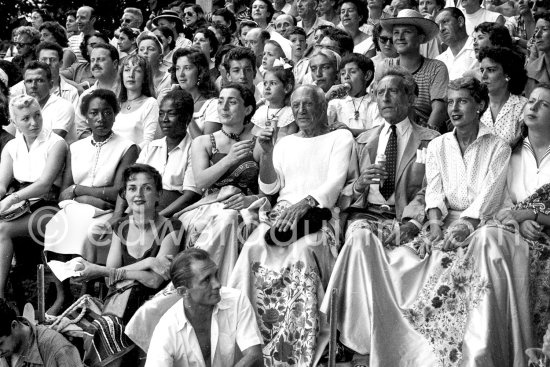 At a local Corrida. During a break, Jacqueline is getting a suck of Picasso's ice cream cornet; in the background Maya, Claude, Paloma; on right Jean Cocteau, Francine Weisweiller. Vallauris 11 Aug 1955. - Photo by Edward Quinn