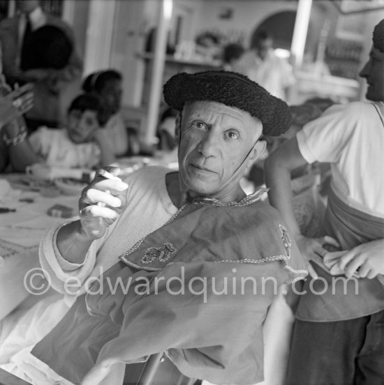 Pablo Picasso with hat and cape of a toreador at the lunch given for his friends at restaurant Le Vallauris before the bullfight. Claude Picasso in the background. Vallauris 1955. - Photo by Edward Quinn
