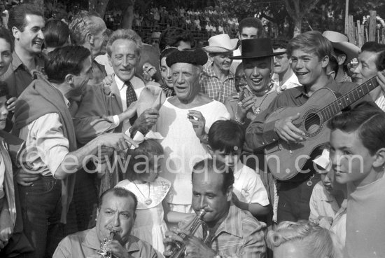 At Pablo Picasso\'s arrival on the village square where the corrida is to be held the band blares out some of his favourite Spanish melodies. From left: Javier Vilató, Jacques-Henri Lartigue, photographer, Jean Cocteau, Jacqueline, Pablo Picasso, Maya Picasso, Paloma Picasso and Claude Picasso, with the guitar the son of writer José Herrera-Petere. Vallauris 1955. - Photo by Edward Quinn