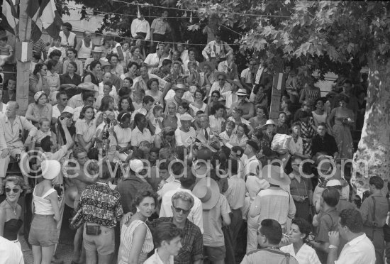 On the grandstand of a bullfight put on in his honor, Pablo Picasso surrounded by his family and friends is signing autographs. Vallauris 1955. - Photo by Edward Quinn