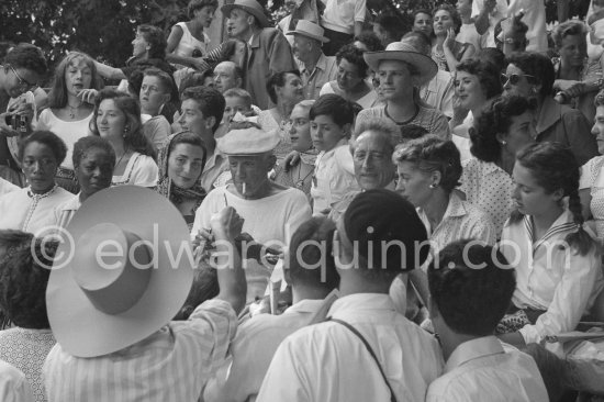 On the grandstand of a bullfight put on in his honor, Pablo Picasso is signing autographs. On the left of Pablo Picasso Jacqueline, on the right Jean Cocteau and Francine Weisweiller and her daughter Carole, behind Pablo Picasso his children Maya Picasso and Claude Picasso. Vallauris 1955. - Photo by Edward Quinn