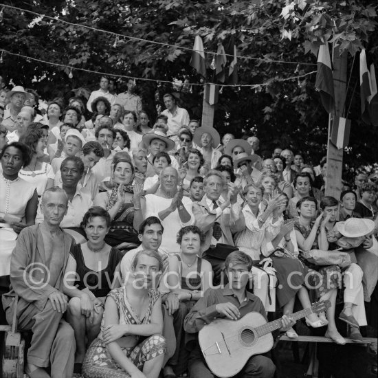 Pablo Picasso on the grandstand at the corrida surrounded by his family and friends. Lartigue and his wife Florette, Vilató and wife Germaine Lascaux, Jacqueline, Maya Picasso, Jean Cocteau, Francine Weisweiller, Dr. Jeanne Creff (acupuncturist of Pablo Picasso), with the guitar the son of the writer José Herrera-Petere. Vallauris 1955. - Photo by Edward Quinn