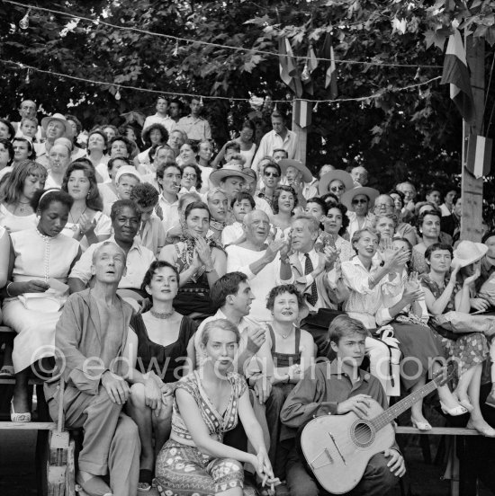 Pablo Picasso on the grandstand at the corrida surrounded by his family and friends. Lartigue and his wife Florette, Vilató and wife Germaine Lascaux, Jacqueline, Maya Picasso, Jean Cocteau, Francine Weisweiller, Dr. Jeanne Creff (acupuncturist of Pablo Picasso), with the guitar the son of the writer José Herrera-Petere. Vallauris 1955. - Photo by Edward Quinn