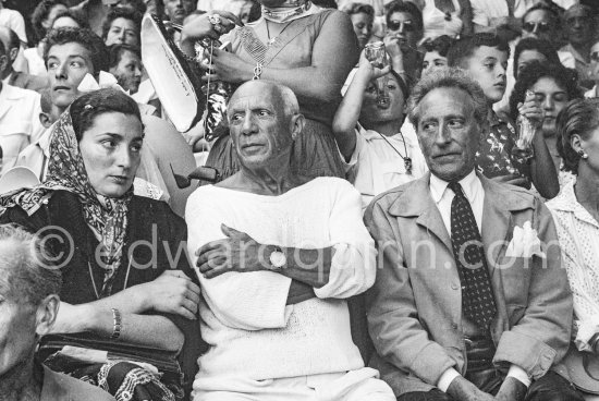 On the grandstand of a bullfight put on in Pablo Picasso's honor. From left: Jacqueline, Pablo Picasso, Jean Cocteau. Behind them with the Coke bottle Claude Picasso. Vallauris 1955. - Photo by Edward Quinn