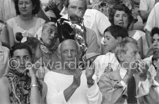 On the grandstand of a bullfight put on in Pablo Picasso's honor. From left: Jacqueline, Pablo Picasso, Jean Cocteau. Behind them Paloma Picasso, Maya Picasso and Claude Picasso. Vallauris 1955. - Photo by Edward Quinn