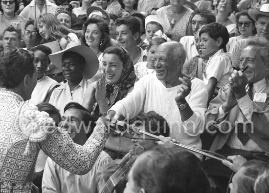 On the grandstand of a bullfight put on in Pablo Picasso's honor. From left: Bandrillero andaluz Francisco Reina, "El Minuni", Javier Vilató, Jacqueline, Pablo Picasso, Jean Cocteau. Behind them Paloma Picasso, Maya Picasso and Claude Picasso. Vallauris 1955. - Photo by Edward Quinn