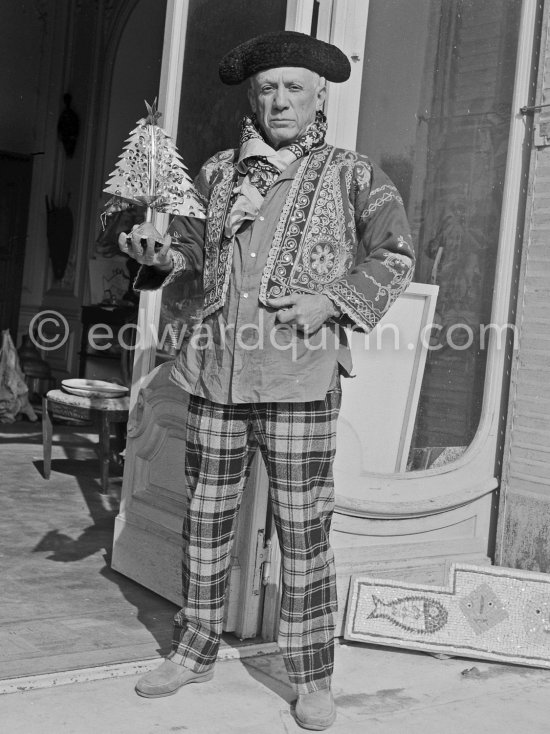 Pablo Picasso in a whimsical costume. Among other things, he has on a bullfighter’s jacket, given to him by his friend, the famous matador Dominguin. On the floor a mosaic Hjalmar Boyesen executed after a Pablo Picasso design. In front of the garden gate at La Californie. Cannes 1956. - Photo by Edward Quinn