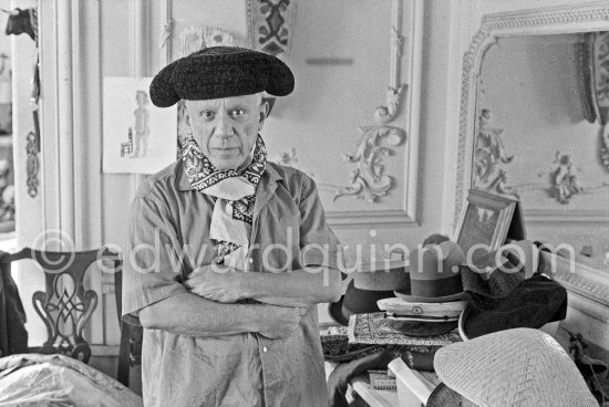 To strike a pose, Pablo Picasso tries on hats from his collection for his own amusement and that of his guests. La Californie, Cannes 1956. - Photo by Edward Quinn
