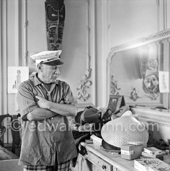 To strike a pose, Pablo Picasso tries on hats from his collection for his own amusement and that of his guests. La Californie, Cannes 1956. - Photo by Edward Quinn