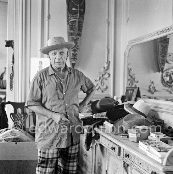 To strike a pose, Pablo Picasso tries on hats from his collection for his own amusement and that of his guests. La Californie, Cannes 1956. - Photo by Edward Quinn
