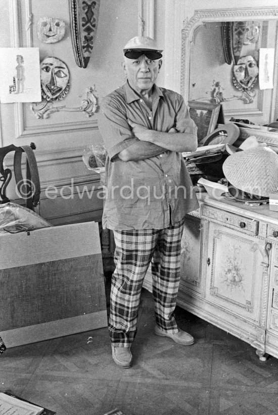 To strike a pose, Pablo Picasso tries on hats from his collection for his own amusement and that of his guests. La Californie, Cannes 1956. - Photo by Edward Quinn