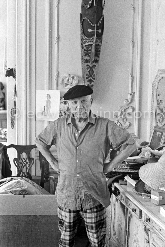 To strike a pose, Pablo Picasso tries on hats from his collection for his own amusement and that of his guests. La Californie, Cannes 1956. - Photo by Edward Quinn