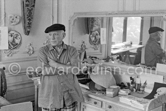 To strike a pose, Pablo Picasso tries on hats from his collection for his own amusement and that of his guests. La Californie, Cannes 1956. - Photo by Edward Quinn